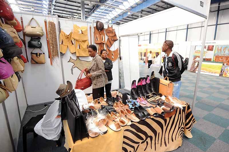 Visitors exploring locally made leather crafts at a market stall