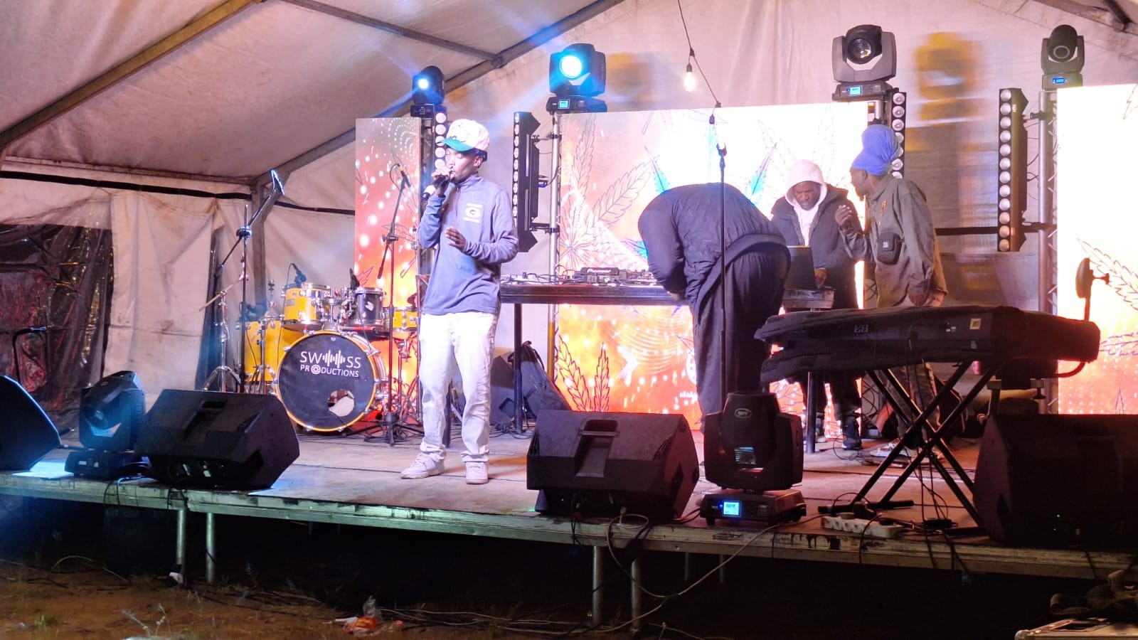Musicians playing live instruments on a stage under a marquee