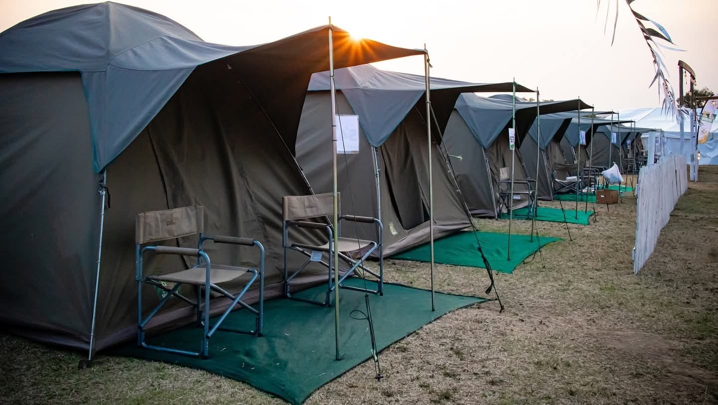 Camping tents with outdoor chairs set up along a walkway