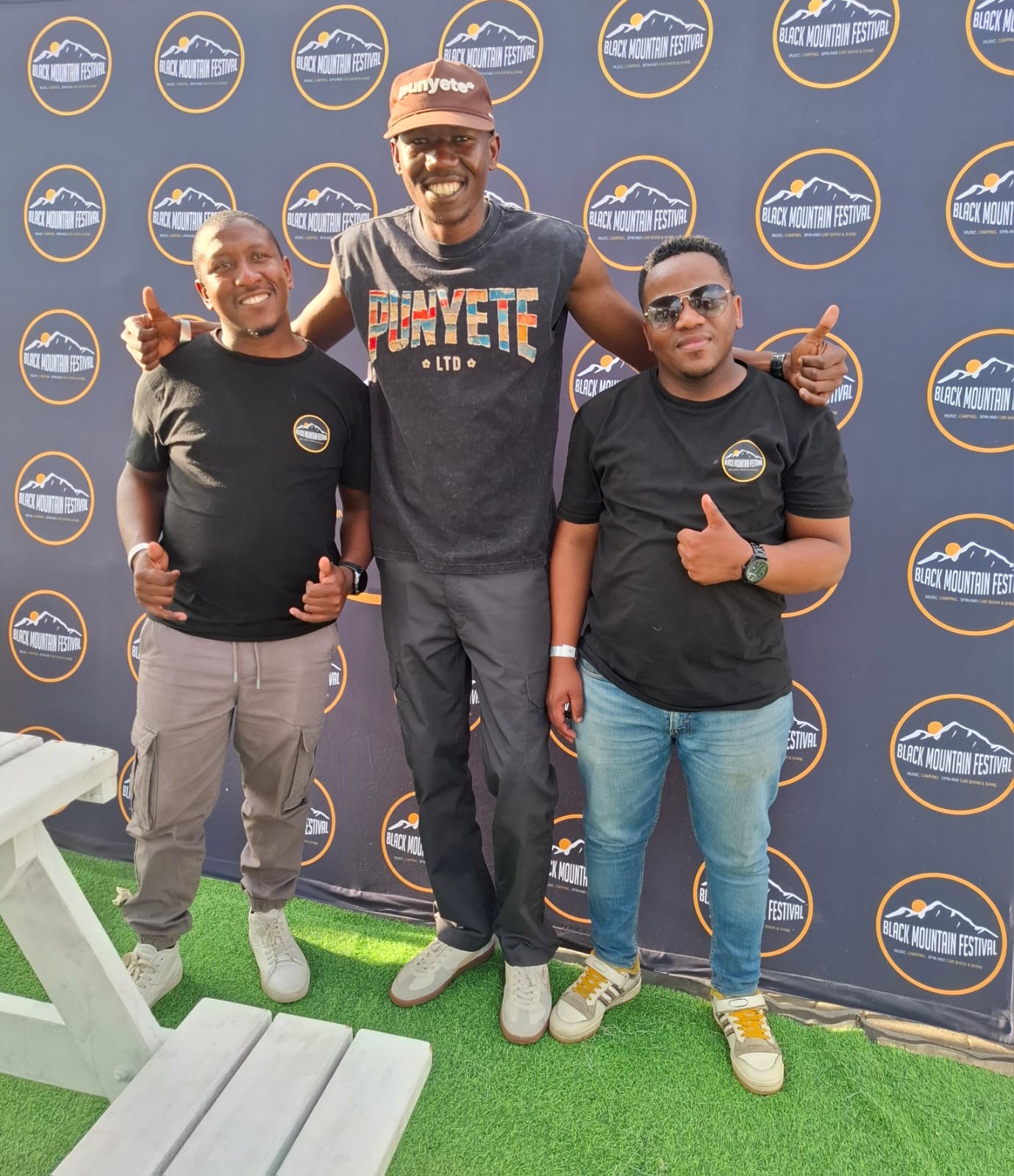 Three festival visitors posing together in front of a Black Mountain Festival backdrop