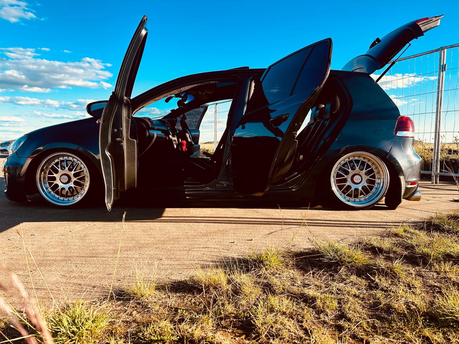 A modified car with its doors raised at an outdoor show