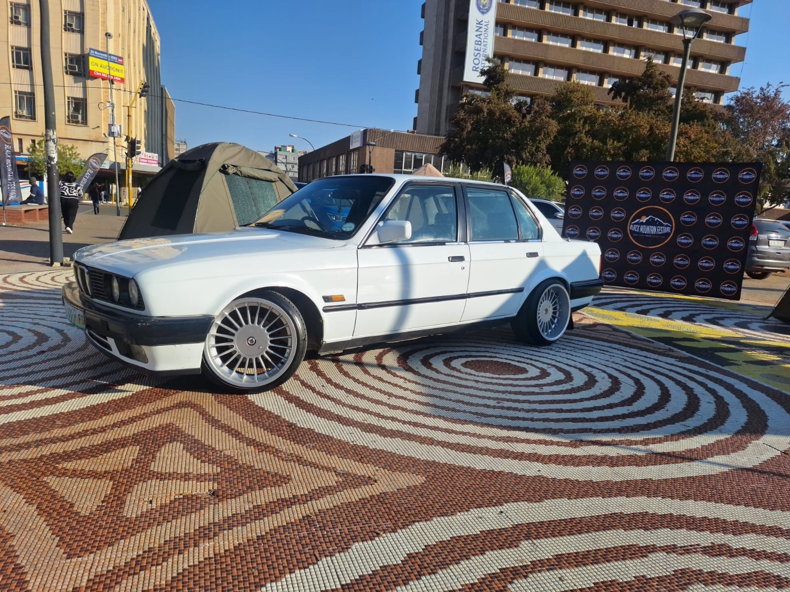 A white classic car displayed in a courtyard